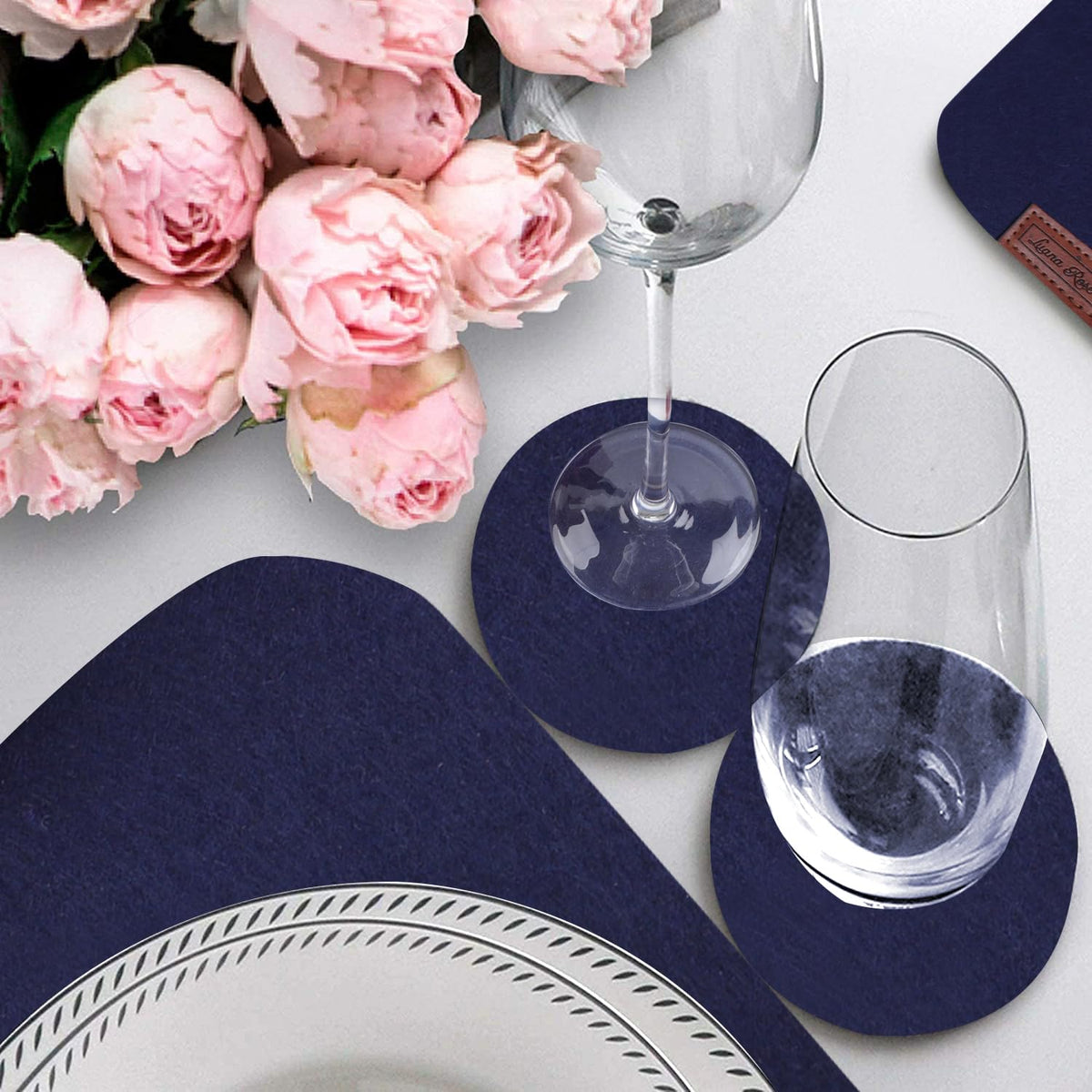 Filz Tischset - 12-teilig inkl. Glasuntersetzer - Blau mit runden Glasuntersetzern und dezentem Design auf hellem Tisch neben rosa Rosen.