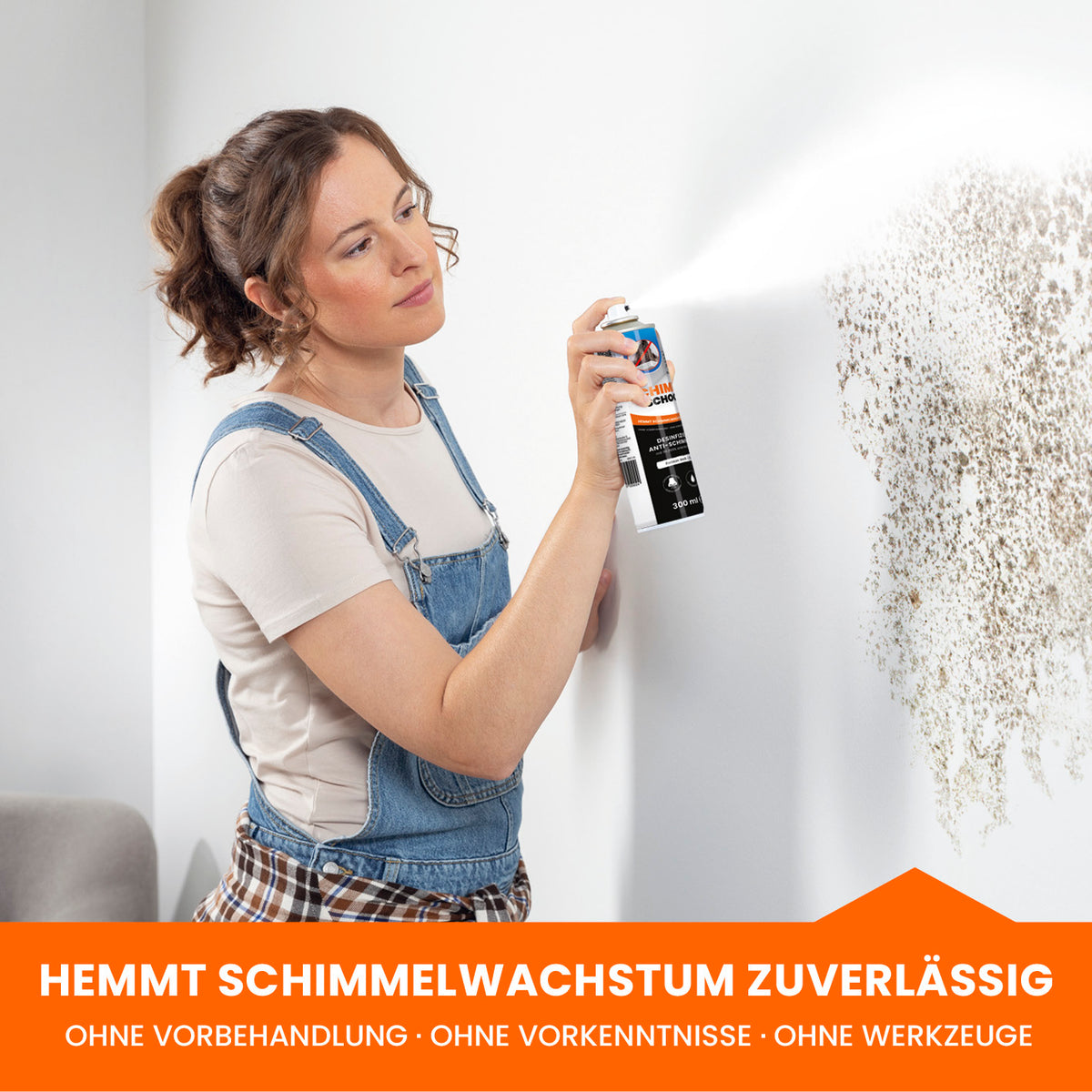 Frau sprüht Tonis SCHIMMELSCHOCK 5.2 Anti-Schimmel-Farbe - Weiß direkt auf schimmelbefallene Wand zur effektiven Schimmelbekämpfung.