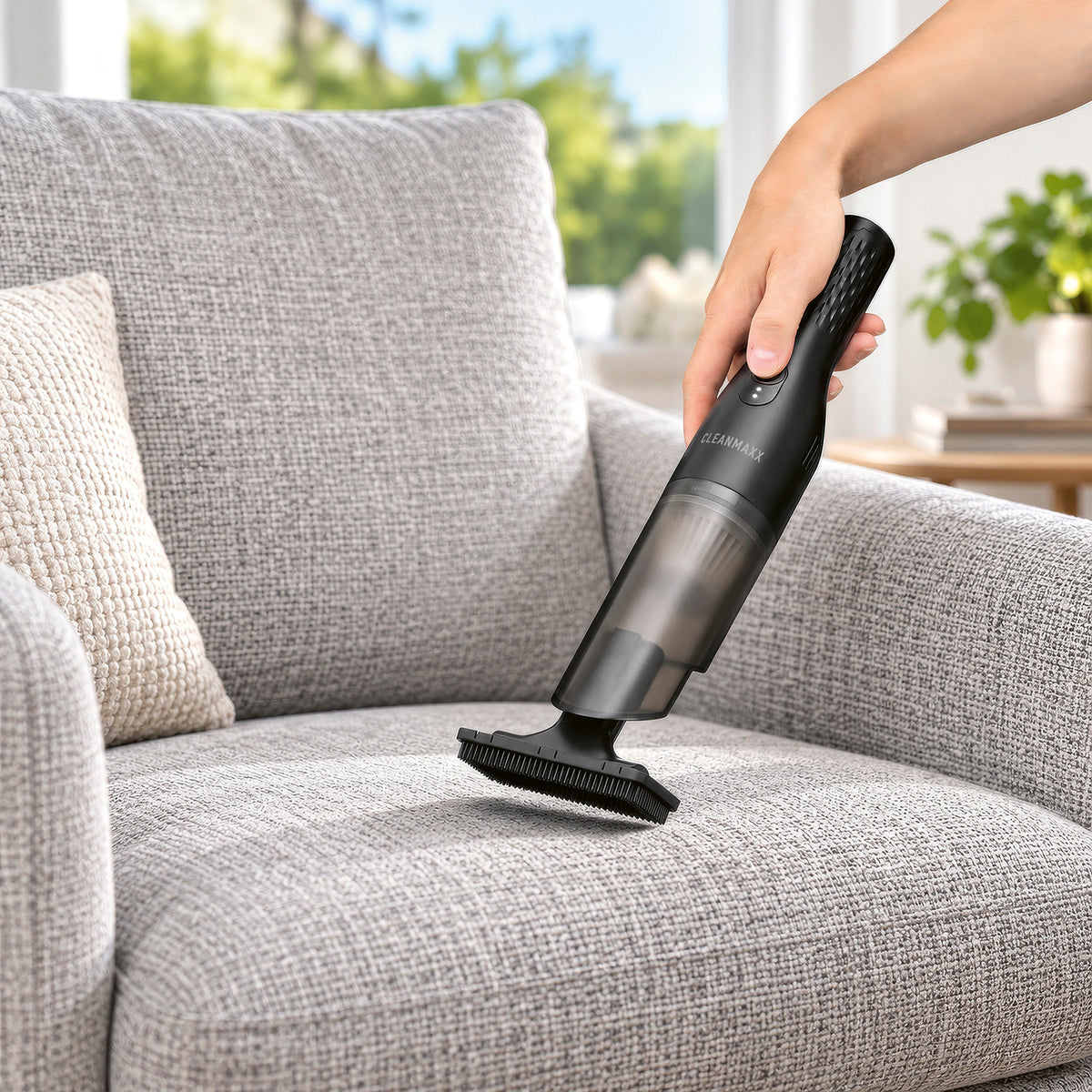 Akku-Handstaubsauger - Schwarz beim Reinigen eines Sofas mit Bürstenaufsatz