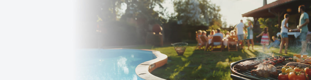 Ein gefüllter Kugelgrill steht an einem Pool, dahinter sitzen Menschen im Garten an einem Tisch, daneben ein Feuerkorb.