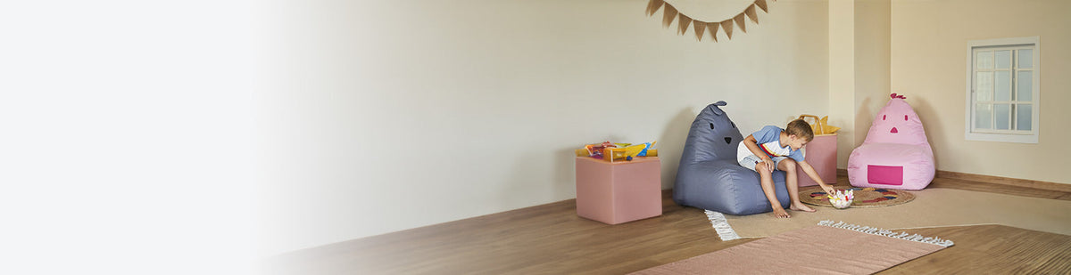 LUMALAND Kinder-Sitzsäcke Chick in einem Kinderzimmer, auf dem Sitzsack sitzt ein kleiner Junge und nascht.