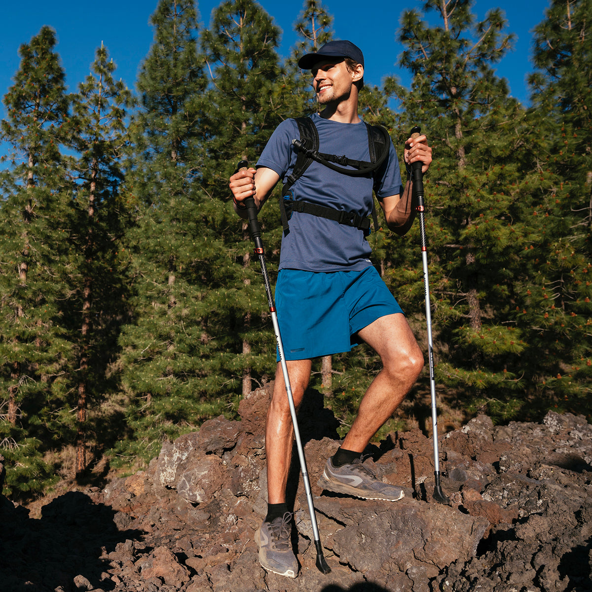 Mann beim Wandern mit Teleskop Wanderstöcke - faltbar - CarbonMix - 63 cm /135 cm in bergigem Gelände bei Sonnenschein