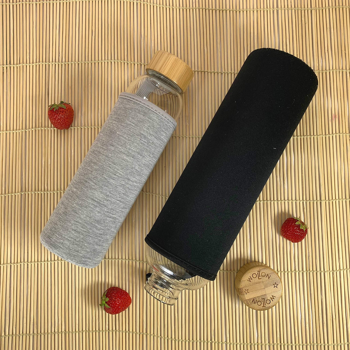 Trinkflasche mit Bambusdeckel - 550 ml - Grau mit grauem Stoffüberzug und separatem schwarzen Überzug, begleitet von frischen Erdbeeren.