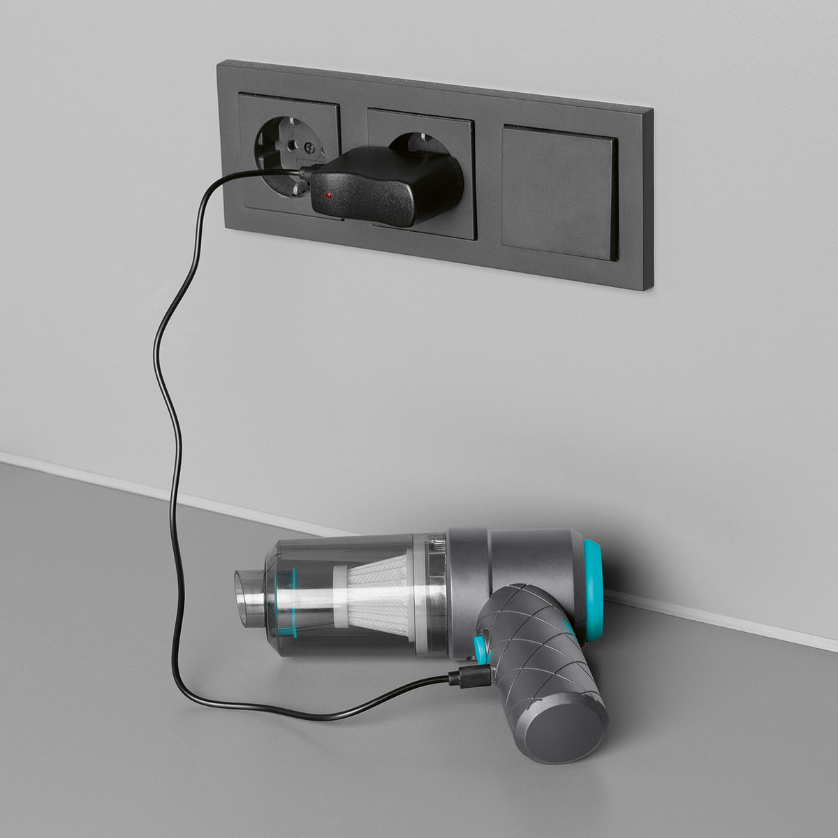 2-in-1-Akkusauger - Grau/Blau beim Laden an einer Steckdose mit angeschlossenem Kabel