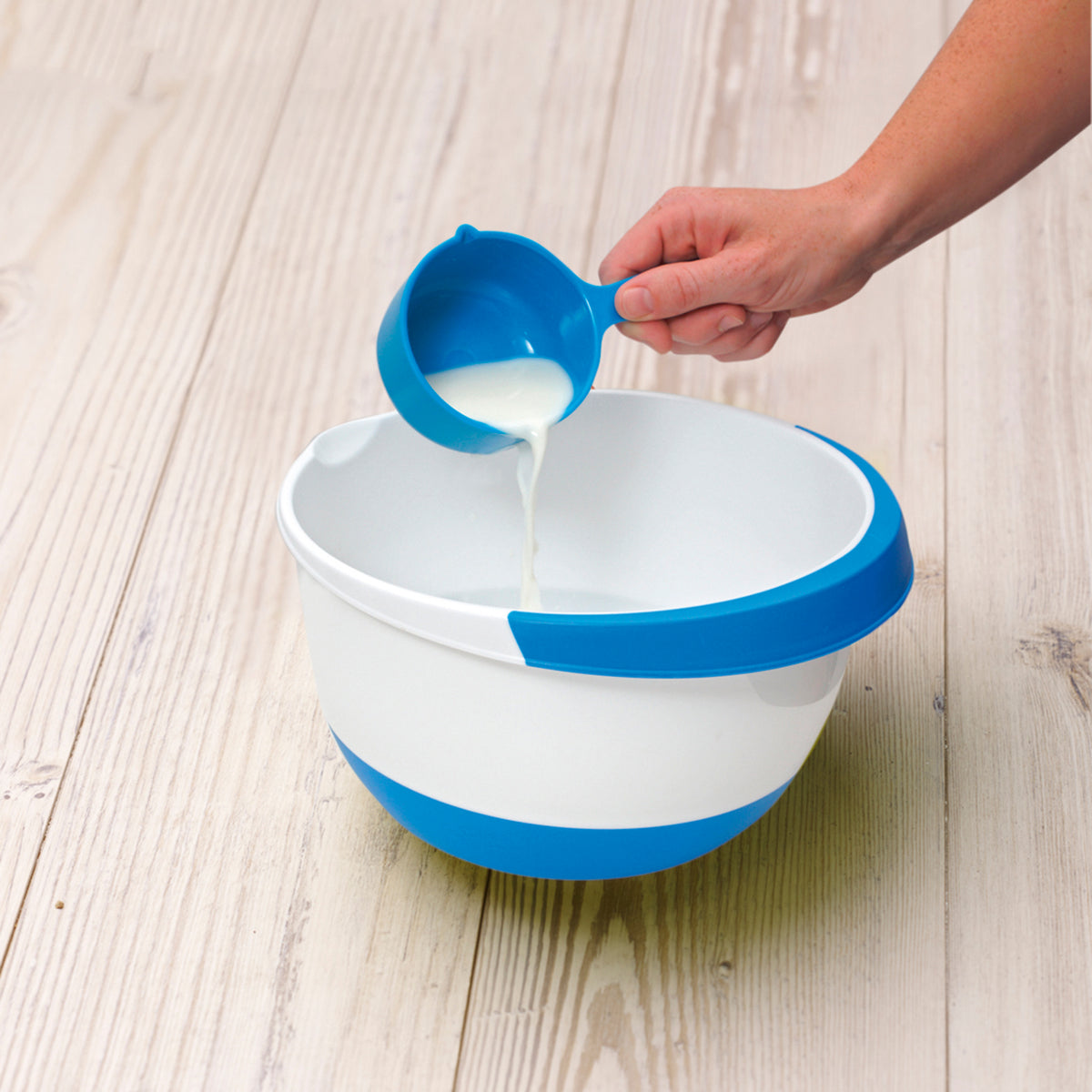 Blaues Messbecher-Set aus Rezeptbuch inkl. Messbecher-Set - Band 1 für Backprofis von morgen, Milch wird in Schüssel gegossen