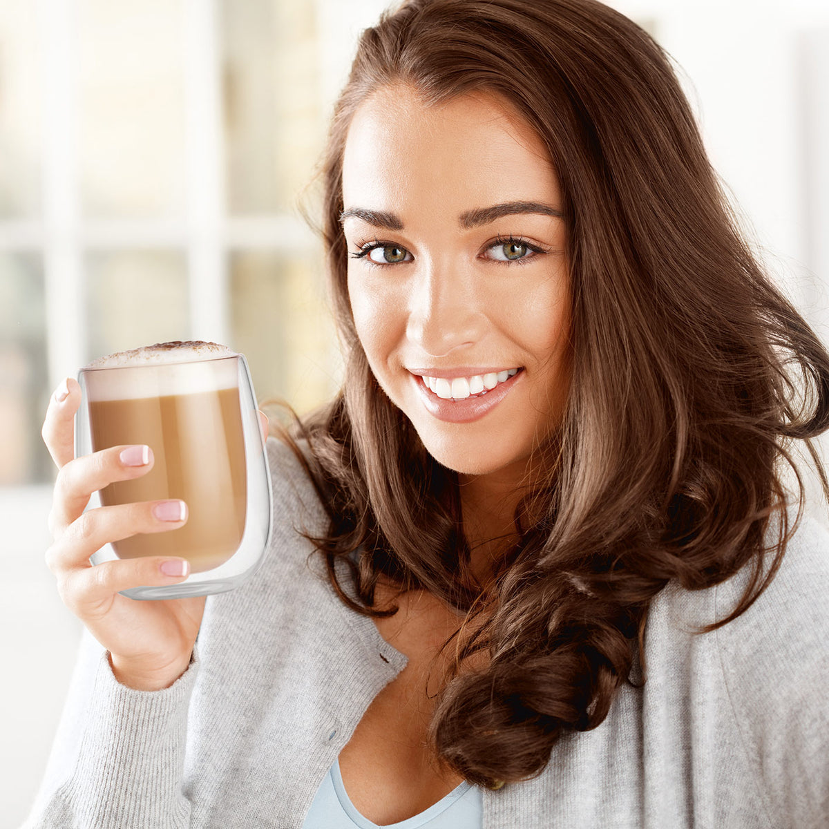 Frau hält ein Cappuccino Thermogläser - 6er-Set aus doppelwandigem Borosilikatglas mit 250 ml Fassungsvermögen.