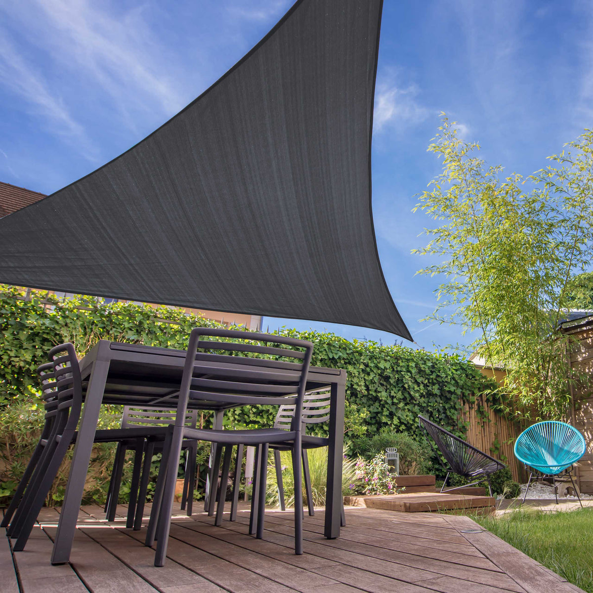 Dunkelgraues Sonnensegel 100% HDPE Dreieck 5x5x5m mit UV-Schutz über Terrasse mit Gartenmöbeln bei Sonnenschein