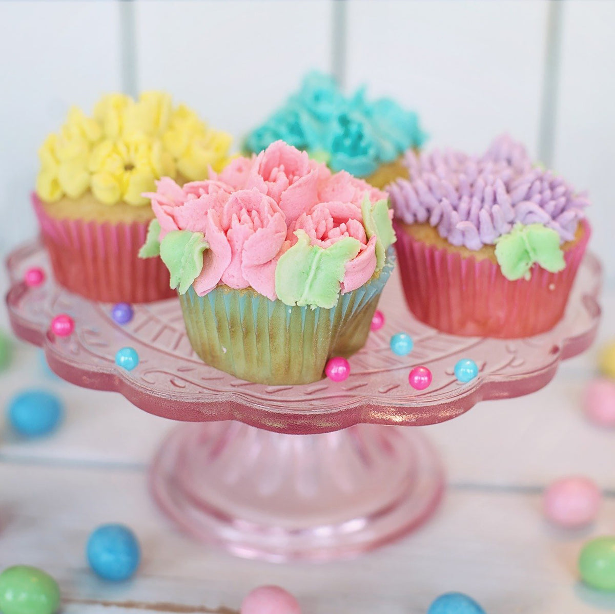 Cupcakes mit bunten, detailreichen Verzierungen, hergestellt mit dem Spritzbeutel-Set mit Tüllen - 67-tlg. auf einem Glasständer.