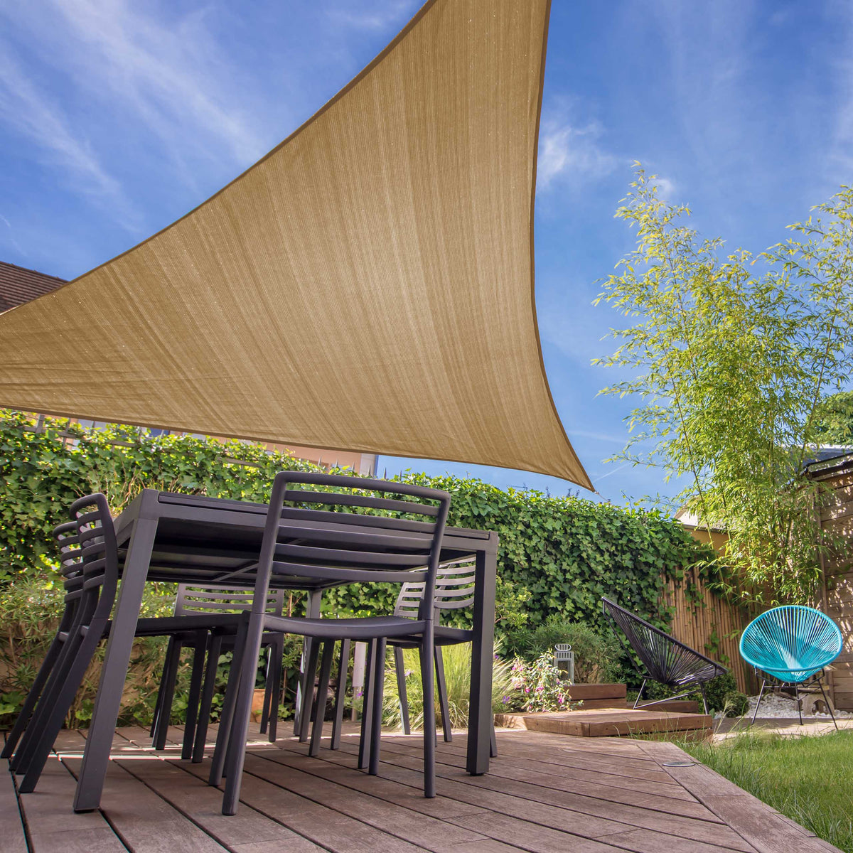 Sonnensegel 100% HDPE mit Stabilisator für UV-Schutz dreieckig 3x3x3 Meter in Sand über Terrasse und Sitzmöbeln.