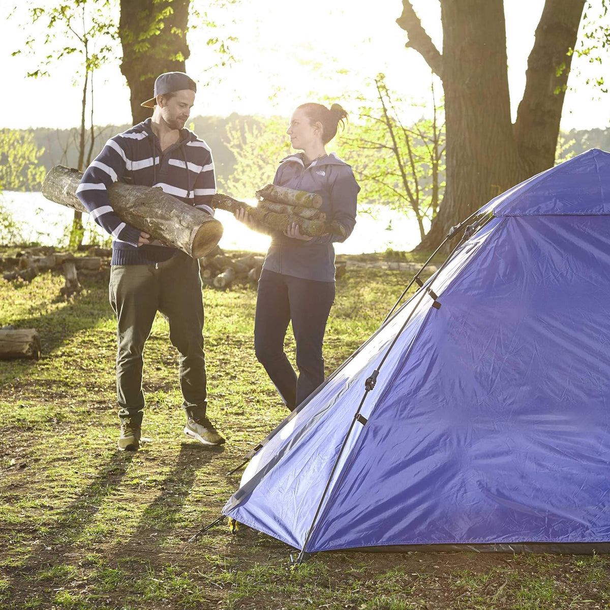 Pop Up Familienzelt Wurfzelt 3 Personen Zelt Blau im Wald, zwei Personen tragen Holz, ideal fürs Camping und Outdoor-Aktivitäten.